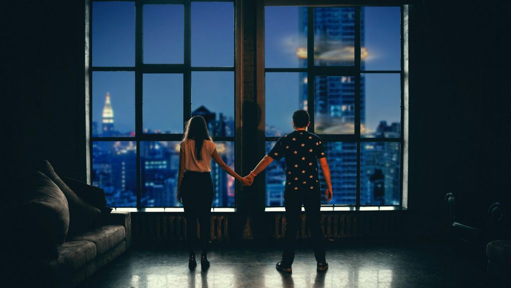 man and woman holding hands in front of glass window