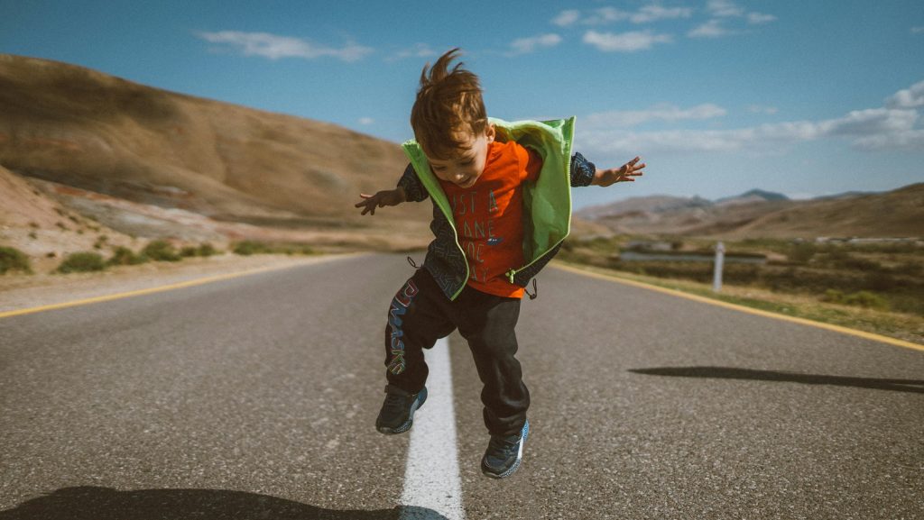a young boy is jumping in the air on a road